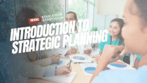 Promotional image for the RHRC Education Symposium titled 'Introduction to Strategic Planning.' A group of people sit around a table with documents and charts, engaged in discussion. The RHRC logo and symposium title appear in the top left corner, with the main title prominently displayed in large white text across the center.