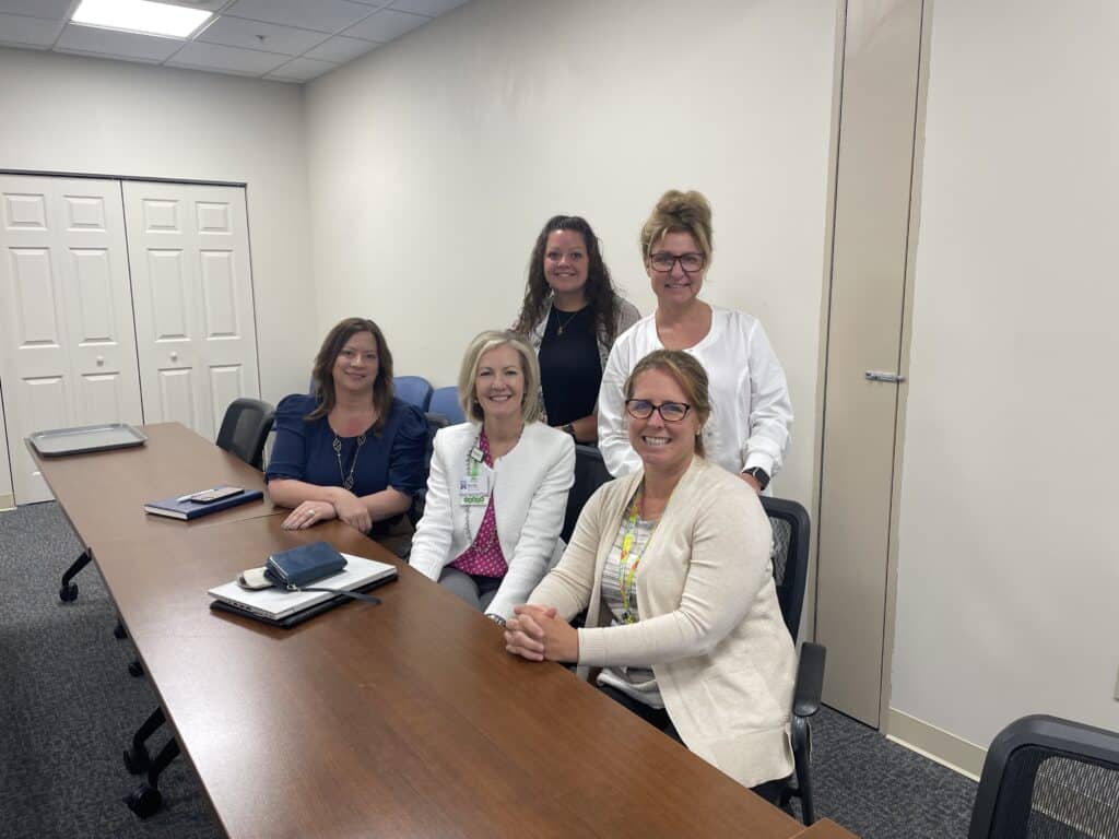Healthcare workers smiling at camera in conference room.