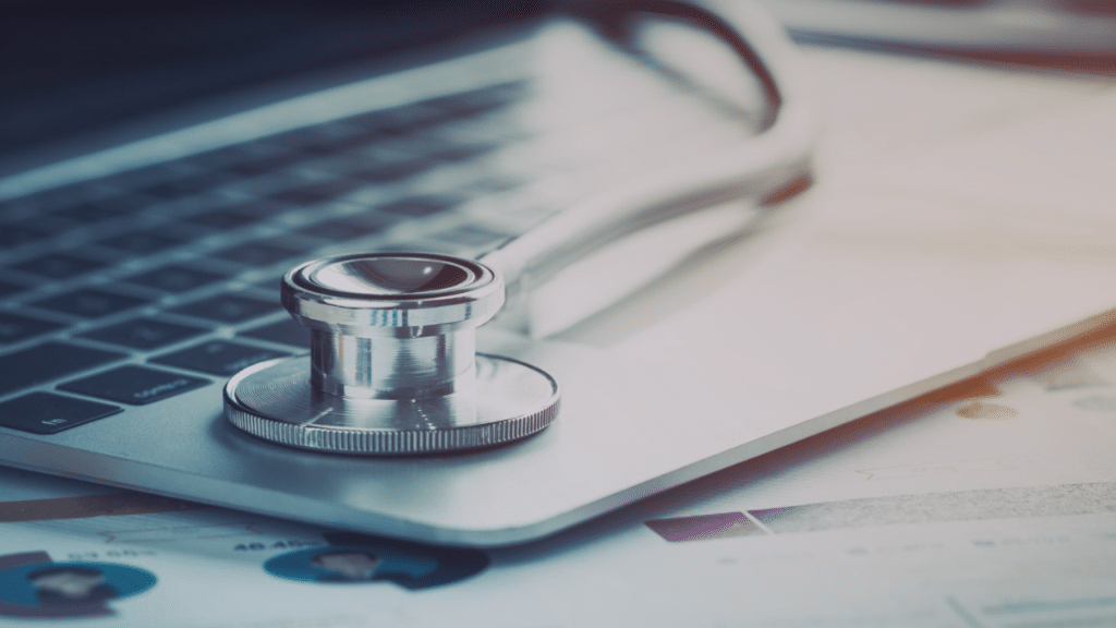 Stethoscope on a laptop computer with healthcare charts and reports in the background