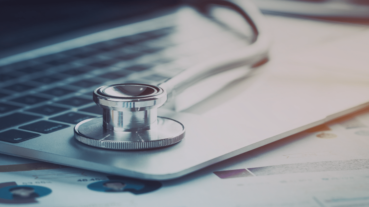 Stethoscope on a laptop computer with healthcare charts and reports in the background